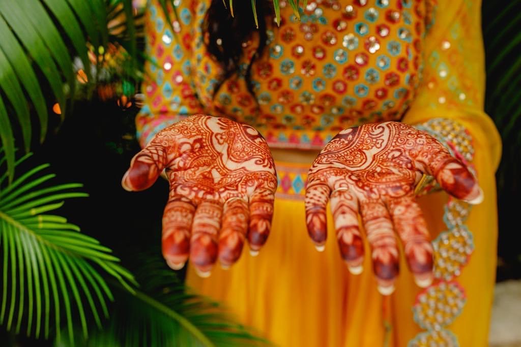 Henna-stained palms against a bright yellow outfit